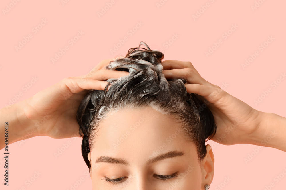Naklejka premium Beautiful young woman washing her hair with shampoo on pink background, closeup