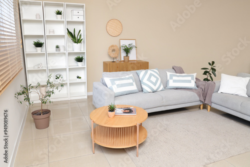 Interior of stylish living room with comfortable sofa, coffee table, shelving unit and houseplant