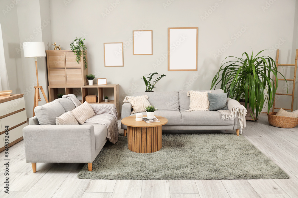 Interior of stylish living room with grey sofas, wooden coffee table and houseplants Interior of stylish living room with grey sofas, wooden coffee table and houseplants
