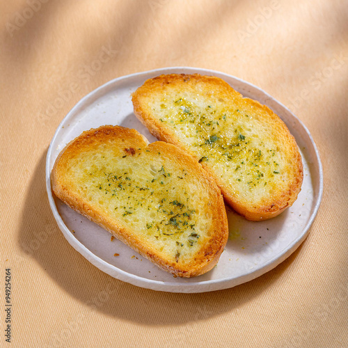 Two slices of toasted, buttery garlic bread sit on a white plate, ready to be devoured.