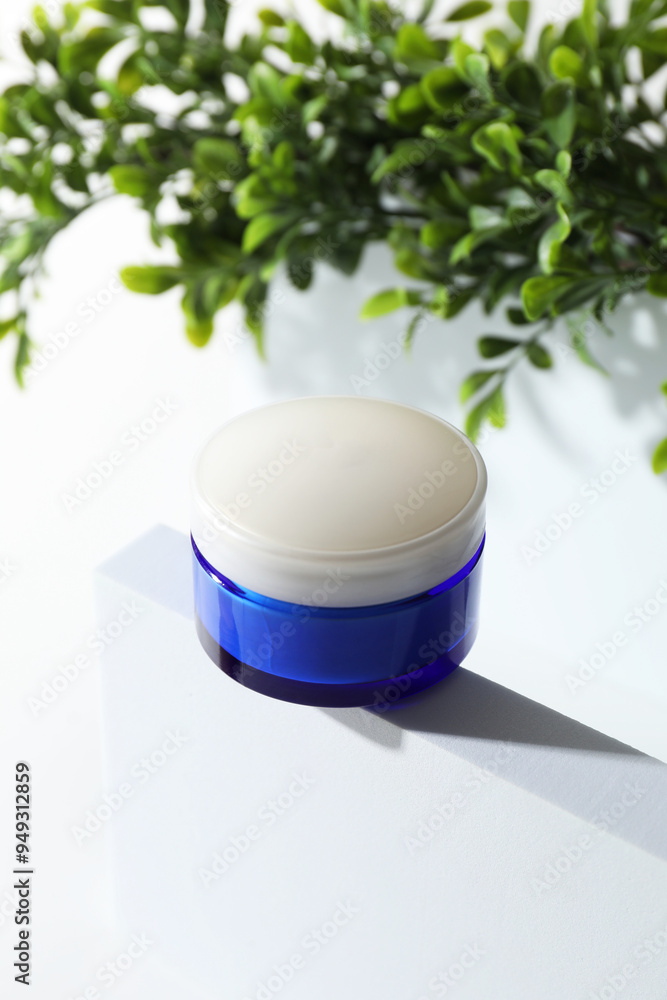 Facial cream in jar and floral decor on white background Facial cream in jar and floral decor on white background