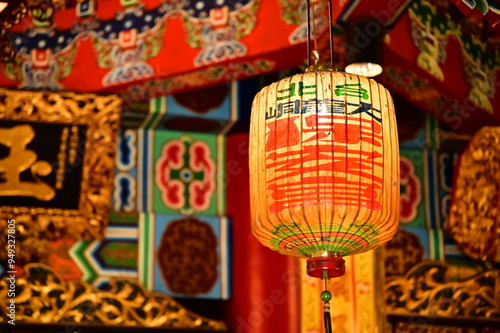 Taiwan - Jan 17, 2024: Close-up of a lantern inside Taipei Bao An Temple, with a grand interior showcasing intricate woodwork and ornate roof details.