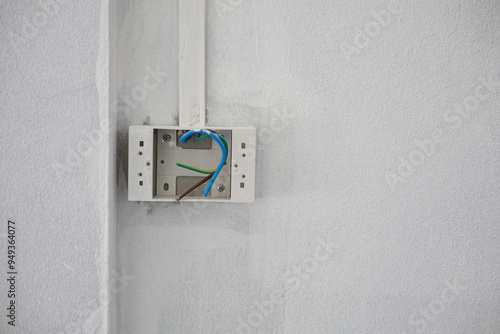 The socket box has wires, plug connection points, and a light switch that has not yet been installed on the cement wall.