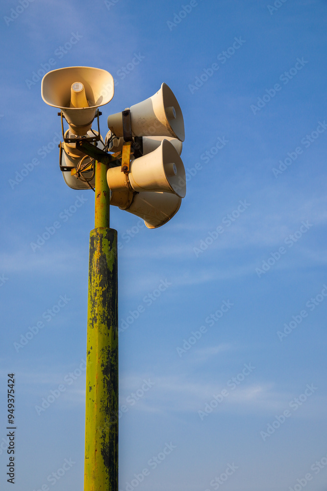 Loudspeaker on pole, alarm siren on blue sky background. public speaker system loudspeakers on blue sky background with copy space. Loudspeaker on pole, alarm siren on blue sky background. public speaker system loudspeakers on blue sky background with copy space.
