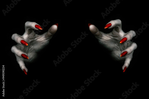 Deadly hands of vampire or monster with sharp bloody red nails in the dark. Witchy fingers hold something invisible, low key, selected focus.