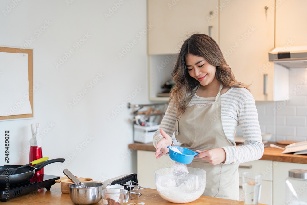 Asian woman enjoying baking with precision in stylish kitchen Asian woman enjoying baking with precision in stylish kitchen
