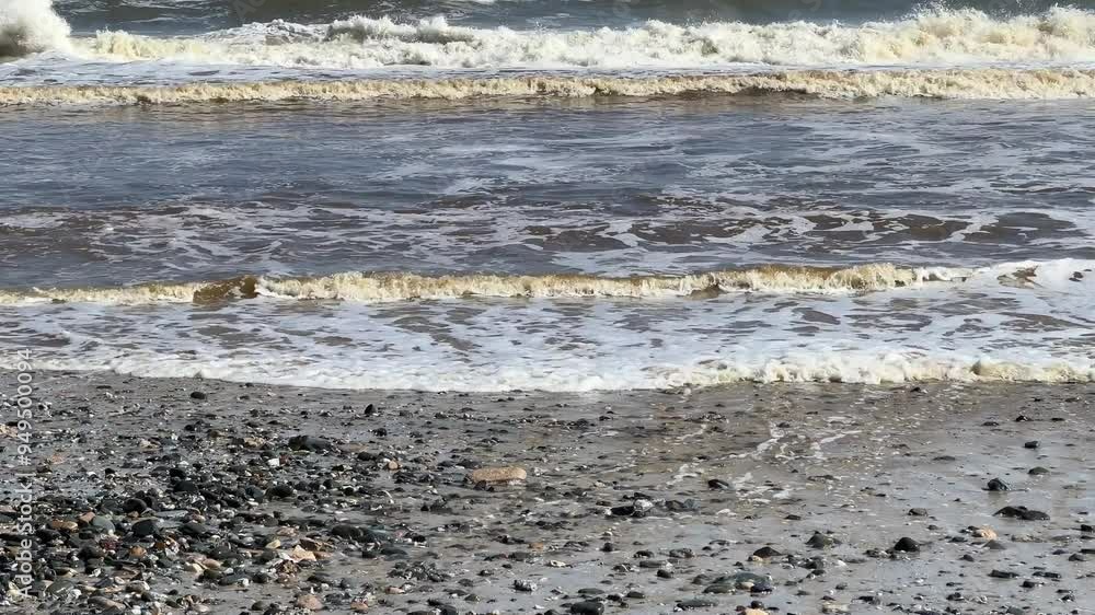 Pebbles washed up on the beach with rolling waves Pebbles washed up on the beach with rolling waves