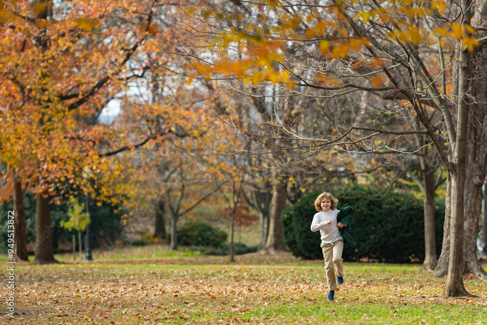 Funny kid running near autumn tree in the autumn park. Active child run and jump in autumn park outdoors. Little kid running near park. Autumn season. Funny kid running near autumn tree in the autumn park. Active child run and jump in autumn park outdoors. Little kid running near park. Autumn season.