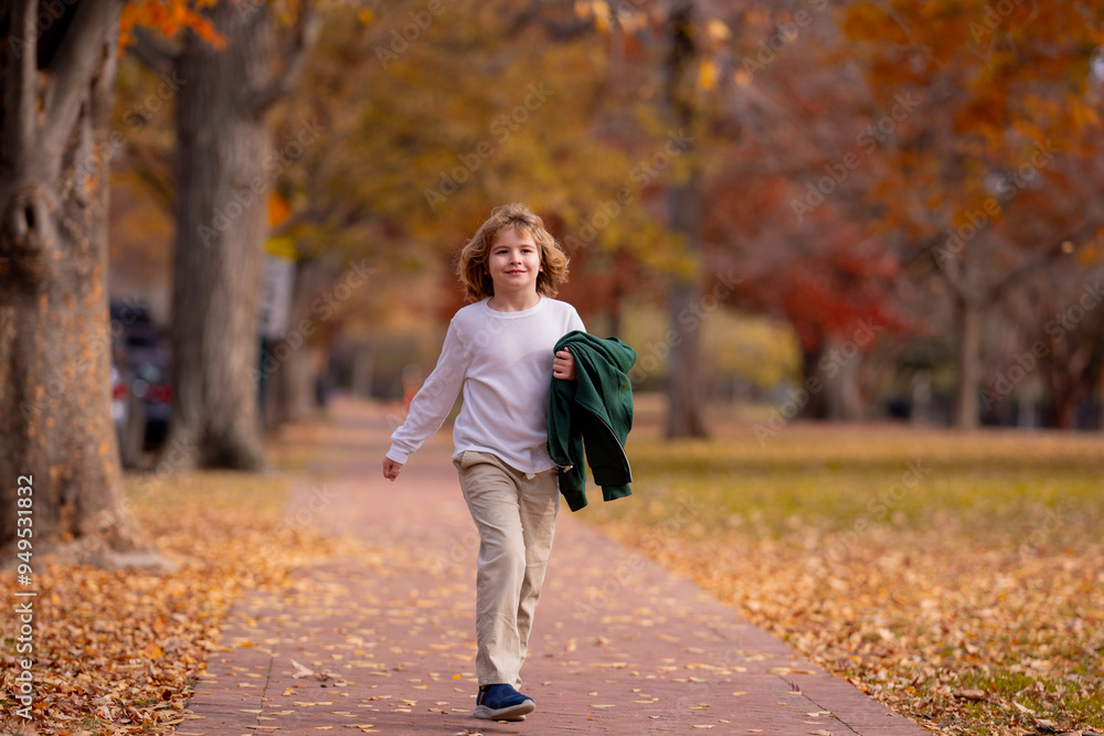 Fototapeta premium Funny kid running near autumn tree in the autumn park. Active child run and jump in autumn park outdoors.