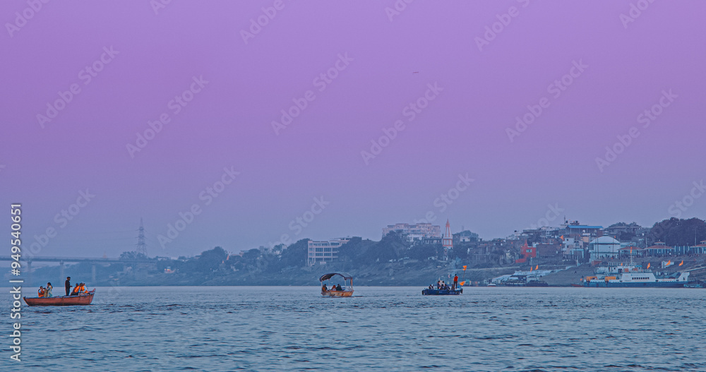 Varanasi, India. Tourists And Pilgrims Floating On Ganga River. Boat Ride On Ganges River. Purple Sunset Sky At Evening . Sacred Waters Of Ganges River. Every Day Life Of India Varanasi, India. Tourists And Pilgrims Floating On Ganga River. Boat Ride On Ganges River. Purple Sunset Sky At Evening . Sacred Waters Of Ganges River. Every Day Life Of India