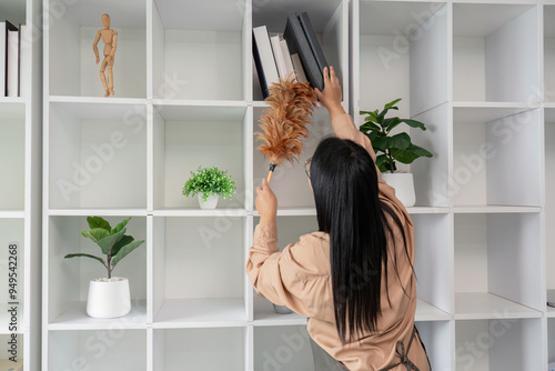 Photos Asian woman dusting office shelves with feather duster