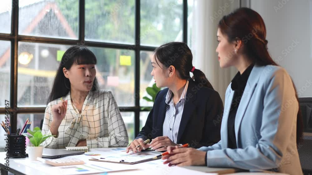 A team of businesswomen is discussing finances. Group of businessmen are brainstorming at their desks in the office. Analyzing financial reports and pointing out financial data on sheets of paper. A team of businesswomen is discussing finances. Group of businessmen are brainstorming at their desks in the office. Analyzing financial reports and pointing out financial data on sheets of paper.