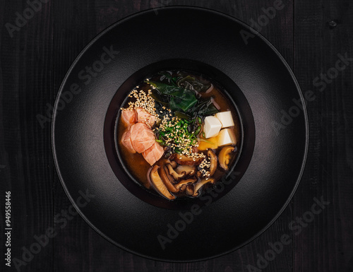 Steaming miso soup with salmon and shiitake mushrooms in black bowl photo