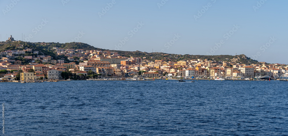 Townscape of La Maddalena village in the namesake archipelago, next to Sardinia, Italy, seen from offshore, surrounded by nature. A famous tourist destination with colorful houses and nature reserve Townscape of La Maddalena village in the namesake archipelago, next to Sardinia, Italy, seen from offshore, surrounded by nature. A famous tourist destination with colorful houses and nature reserve