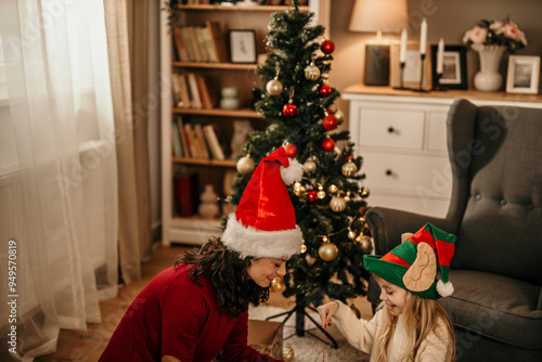 Mother and daughter making presents for Christmas, sitting in the living room next to the tree