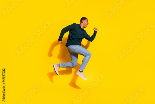 Full size photo of handsome young guy running fast dressed stylish green garment isolated on yellow color background