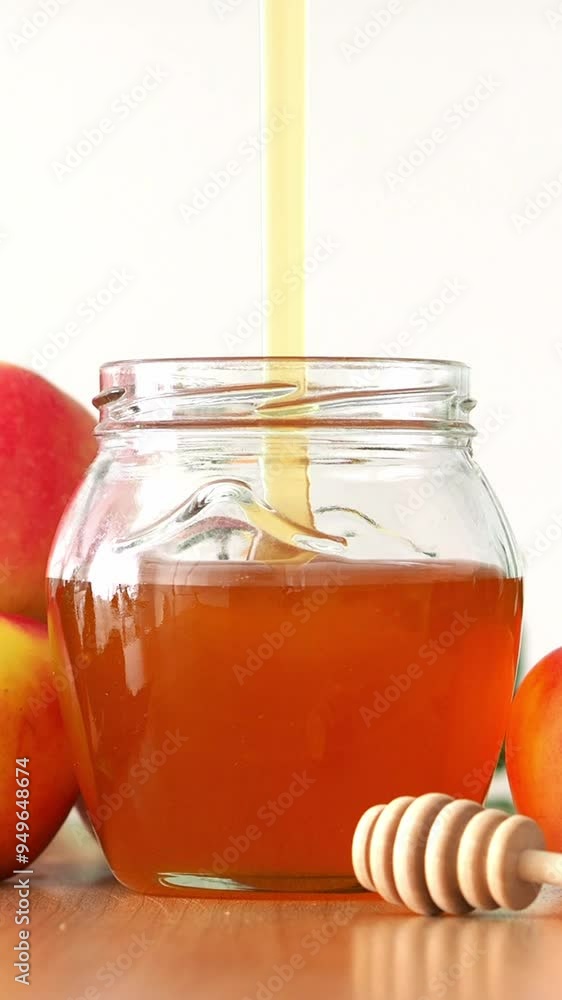 Pour the fresh honey into a glass jar. Liquid honey of fresh harvest is collected with a wooden spoon. Apple and honey saved. Beekeeper's Day. Beekeeper's Business Pour the fresh honey into a glass jar. Liquid honey of fresh harvest is collected with a wooden spoon. Apple and honey saved. Beekeeper's Day. Beekeeper's Business
