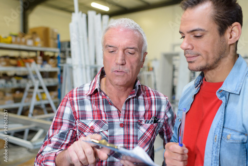 two warehouse workers filling in document