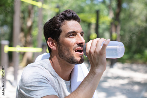 Photos a young man drinking a bottle of water outdoors