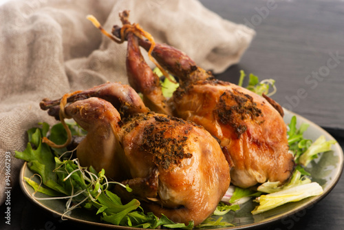 Baked tasty quails on ceramics plate with salad