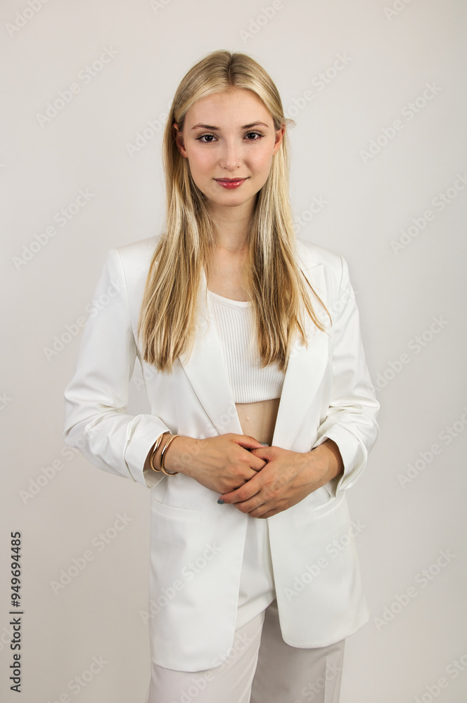 A blonde girl with long hair, model-like appearance, in a white suit, looks intently ahead. A blonde girl with long hair, model-like appearance, in a white suit, looks intently ahead.