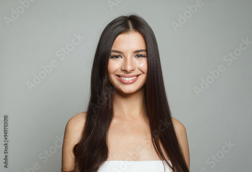 Studio portrait of happy young female model with natural make-up, shiny clean skin and perfect hair. Beautiful woman face