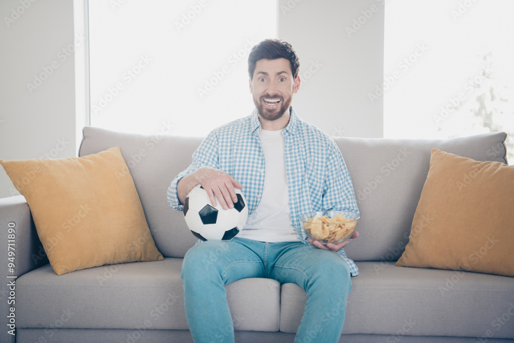 Photo of handsome excited bearded alone mature age man staying home in living room holding football ball watching team game Photo of handsome excited bearded alone mature age man staying home in living room holding football ball watching team game