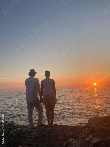 Sunset in Croatia, Pula. Amazing view of the orange sunset with blue sky and clouds on the sea and some trees in the forest in the background with rocky beach. 