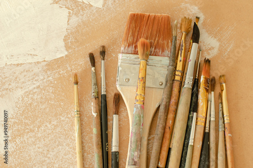 A collection of old painting brushes in working condition placed on a surface with white brushstrokes.