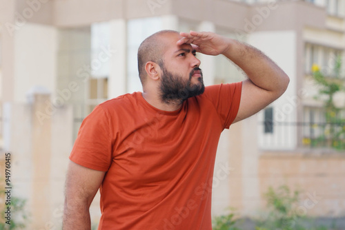 Foto Bald indian Man Looking Around With Hand On Forehead