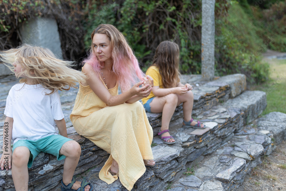 Sad mother sitting on stone steps with her two children in a park Sad mother sitting on stone steps with her two children in a park
