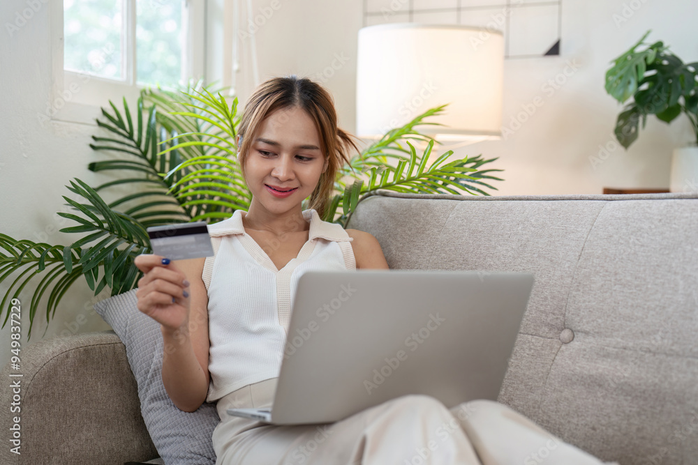 Cheerful Asian woman using credit card for online shopping at home Cheerful Asian woman using credit card for online shopping at home