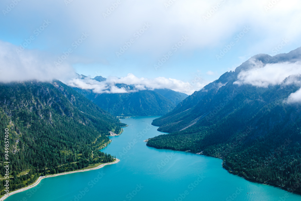 Obraz premium Majestic views of Plansee in Austria with turquoise waters and misty mountains on a sunny day