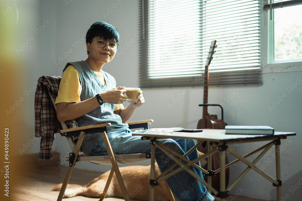 Fototapeta premium Asian embracing LGBTQ identities, smile warmly at the camera, enjoying coffee and guitar near window capturing a joyful and inclusive moment of their lifestyle at home.