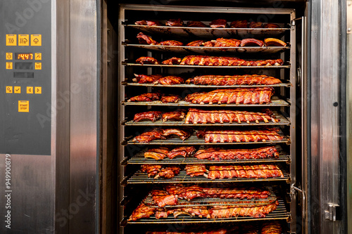 A commercial smoking oven filled with racks of smoked ribs, showcasing the culinary process in a professional kitchen setting. Perfect for food industry, culinary arts, and restaurant-related visuals. photo