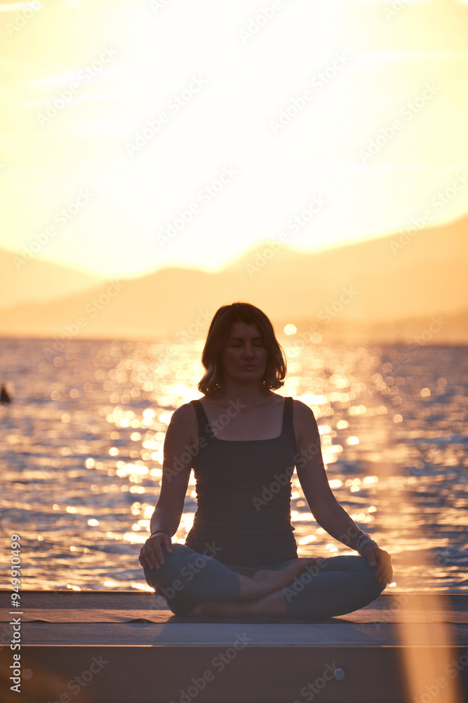 Woman meditating peacefully by the water at sunset with mountains in the background, capturing a moment of tranquility and reflection Woman meditating peacefully by the water at sunset with mountains in the background, capturing a moment of tranquility and reflection