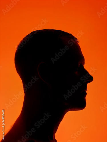 A man's head silhouetted against a vibrant orange background, with his hair and facial features in stark contrast. Silhouette portrait