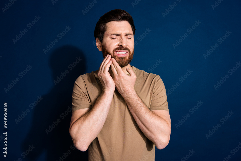 Photo of unhappy man with stylish beard dressed beige t-shirt hold hand on cheek have toothache isolated on dark blue color background Photo of unhappy man with stylish beard dressed beige t-shirt hold hand on cheek have toothache isolated on dark blue color background