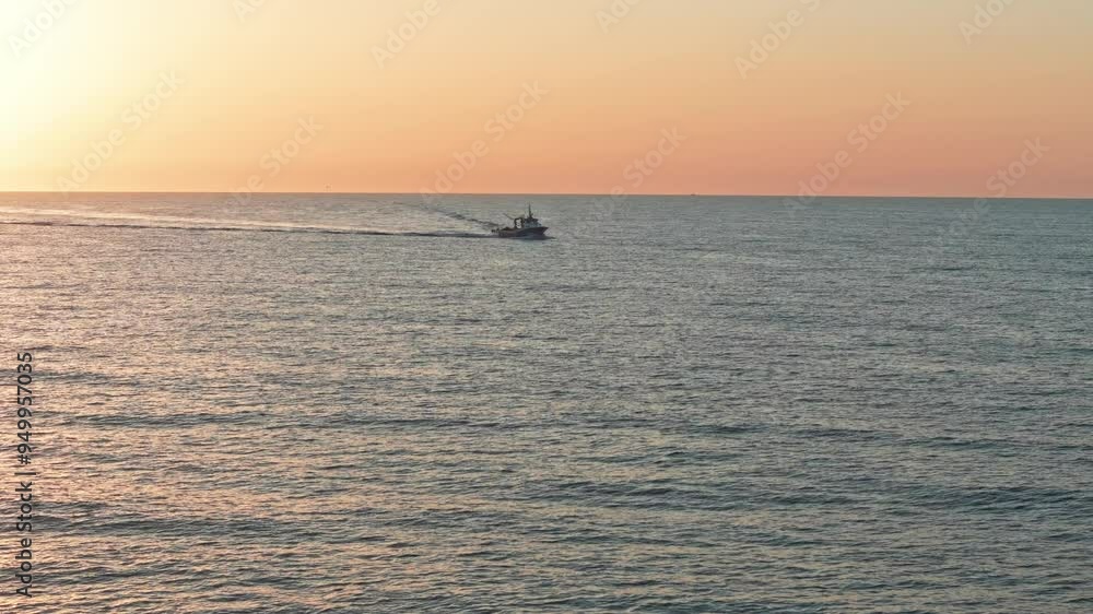 Fishing boat heading home at sunrise, motor running, towing a lifeboat, and creating waves. Filmed from the air in slow motion. Fishing boat heading home at sunrise, motor running, towing a lifeboat, and creating waves. Filmed from the air in slow motion.