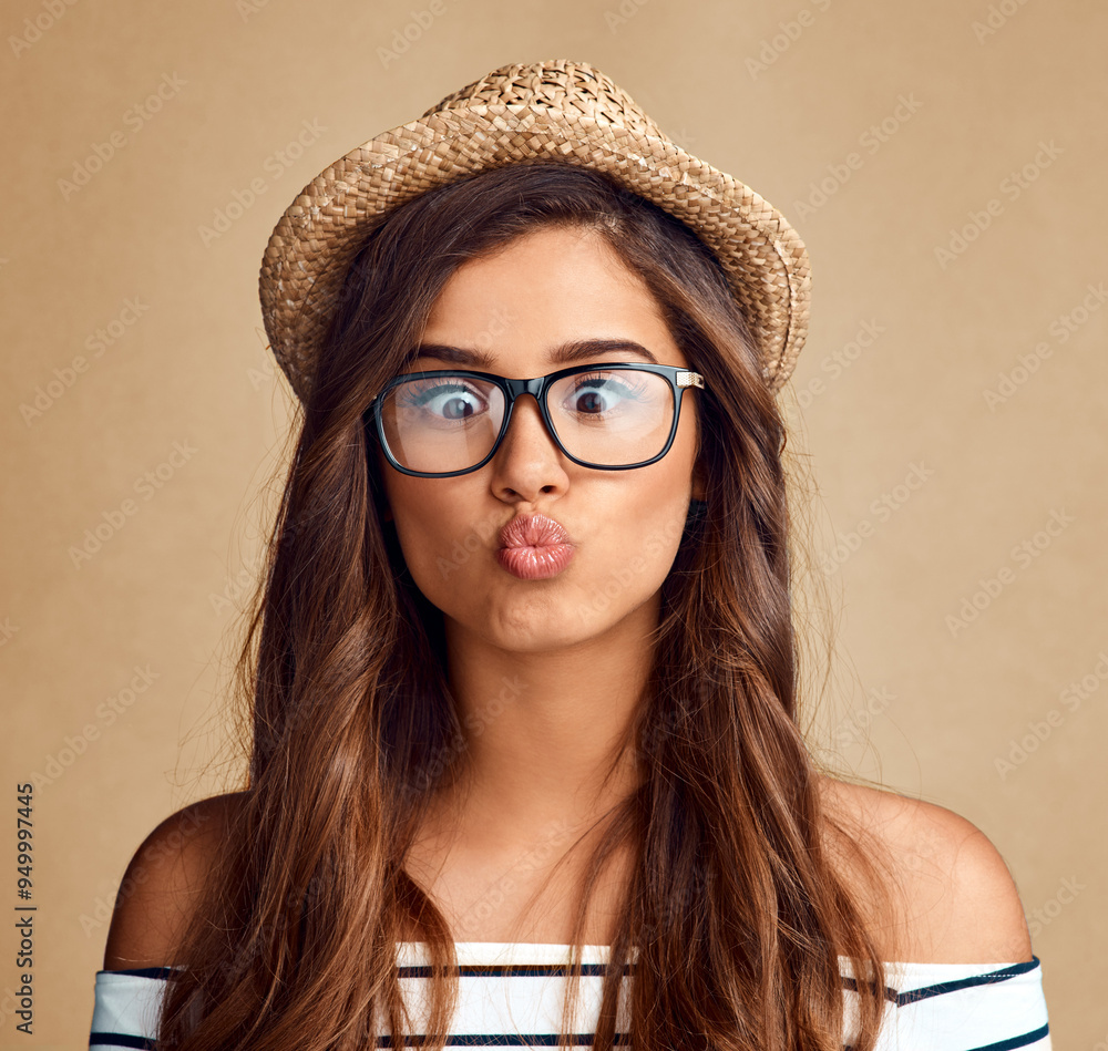 Kiss, woman and funny face with hat in studio for fun game, goofy personality and playing with glasses. Model, person and pout with emoji reaction, expression or confidence with fashion on background Kiss, woman and funny face with hat in studio for fun game, goofy personality and playing with glasses. Model, person and pout with emoji reaction, expression or confidence with fashion on background