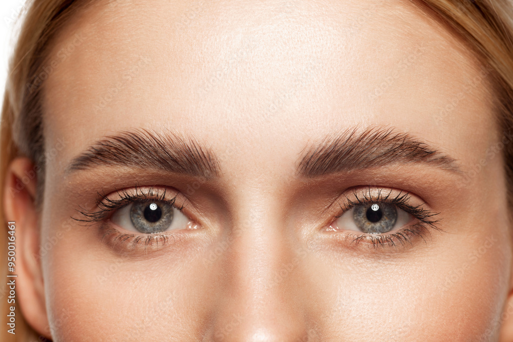 Close-up of beautiful clear female face with attractive gray eyes, perfect eyebrows and natural lashes. Eyebrow and lash lamination. Concept of makeup, cosmetics, natural beauty, skin care products Close-up of beautiful clear female face with attractive gray eyes, perfect eyebrows and natural lashes. Eyebrow and lash lamination. Concept of makeup, cosmetics, natural beauty, skin care products
