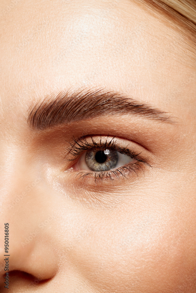 Obraz premium Close-up of beautiful clear female face with attractive gray eyes, perfect eyebrows and natural lashes. Eyebrow and lash lamination, eye lenses, eye care. Concept of makeup, cosmetics, ophthalmology