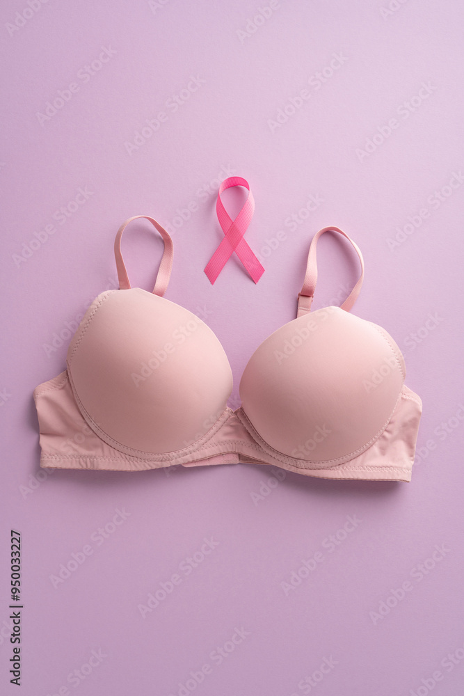Pink vertical ribbon and bra on a soft pink background representing breast cancer awareness and support Pink vertical ribbon and bra on a soft pink background representing breast cancer awareness and support