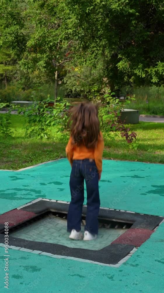 A child enjoys a lively afternoon, bouncing joyfully on a trampoline surrounded by greenery and playground equipment A child enjoys a lively afternoon, bouncing joyfully on a trampoline surrounded by greenery and playground equipment