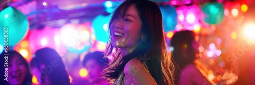 Asian woman dances with friends in lively bar setting surrounded by colorful balloons. Laughing joyful face, vibrant atmosphere, dynamic movement, bright lighting.