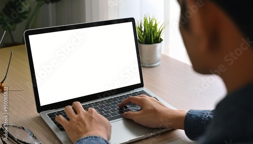 Over shoulder shot of a young man using computer laptop in front of an blank white computer screen in home photo