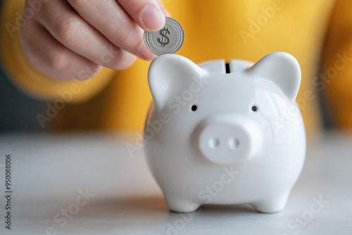 Hand inserting a coin into a white piggy bank for savings concept