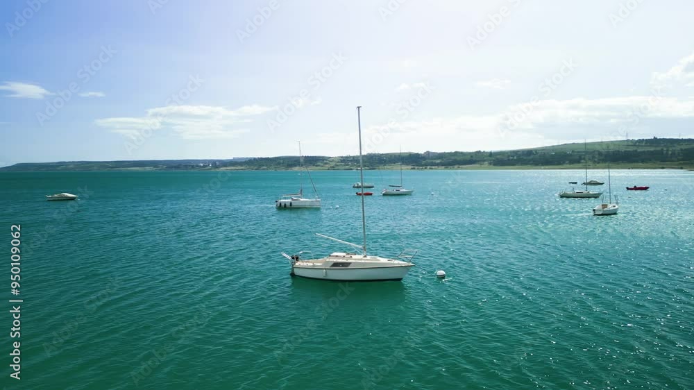 Aerial view, there are small sailing yachts on a small lake, they are anchored and not moving, sunny day and clear sky, the drone flies in a circle around the yacht from left to right Aerial view, there are small sailing yachts on a small lake, they are anchored and not moving, sunny day and clear sky, the drone flies in a circle around the yacht from left to right