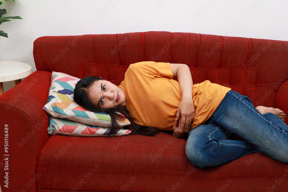 Happy asian woman embracing belly lying on sofa Happy asian woman embracing belly lying on sofa
