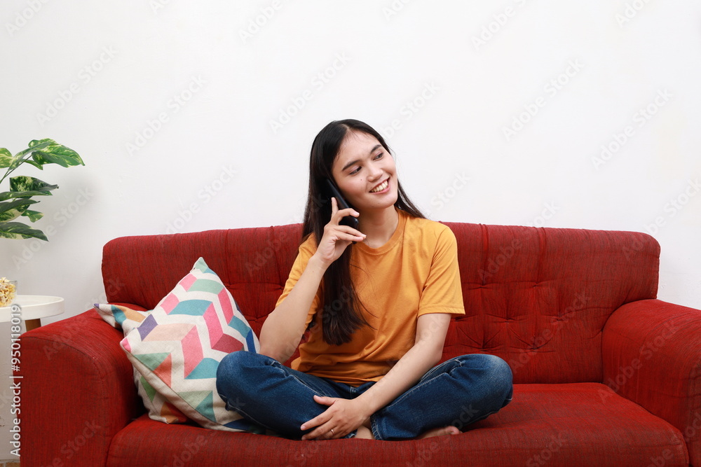 Happy young woman caller talking on phone at home, cheerful enjoying fun mobile conversation, smiling female millennial holding cell talking making call by phone in living room Happy young woman caller talking on phone at home, cheerful enjoying fun mobile conversation, smiling female millennial holding cell talking making call by phone in living room